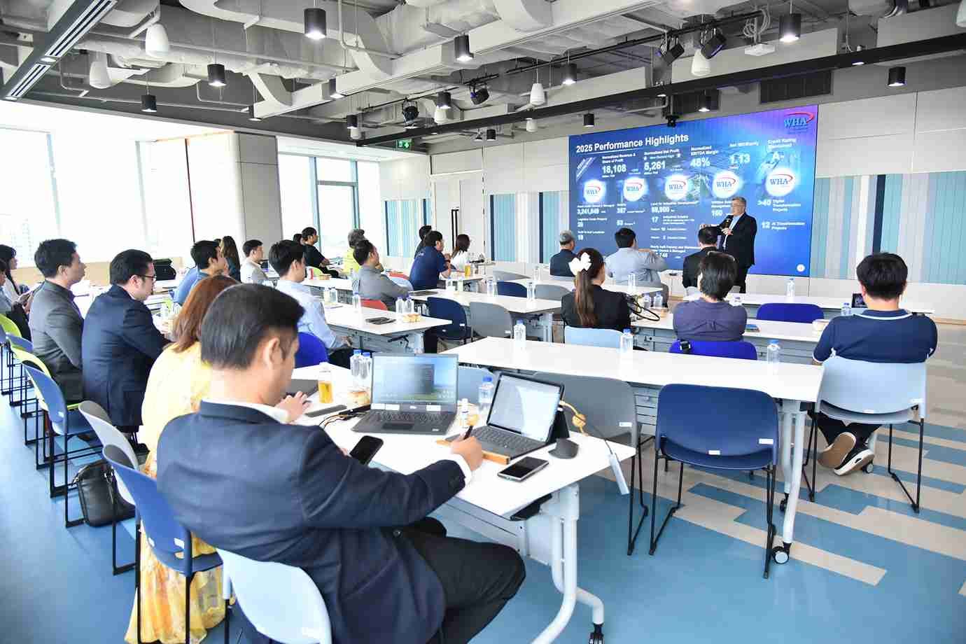 Professionals attend a presentation showing charts on a large screen in a modern room.