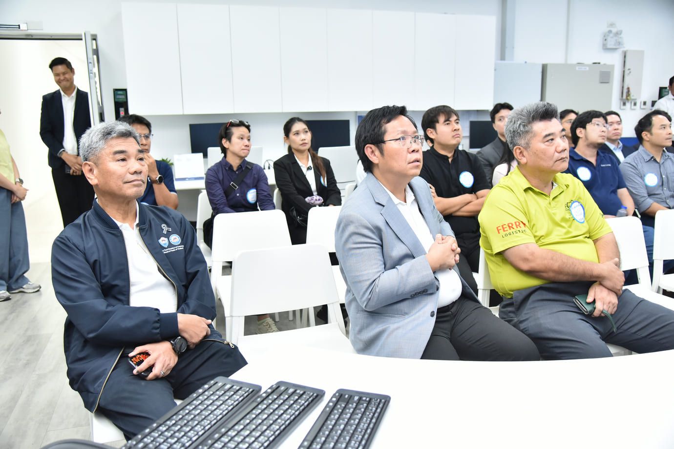 A group of professionals, mostly men, attending a training session in a modern classroom.