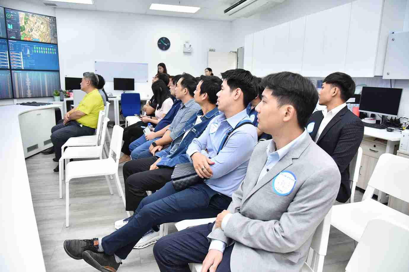 Group of professionals intently observing multi-panel screens in a modern control room.
