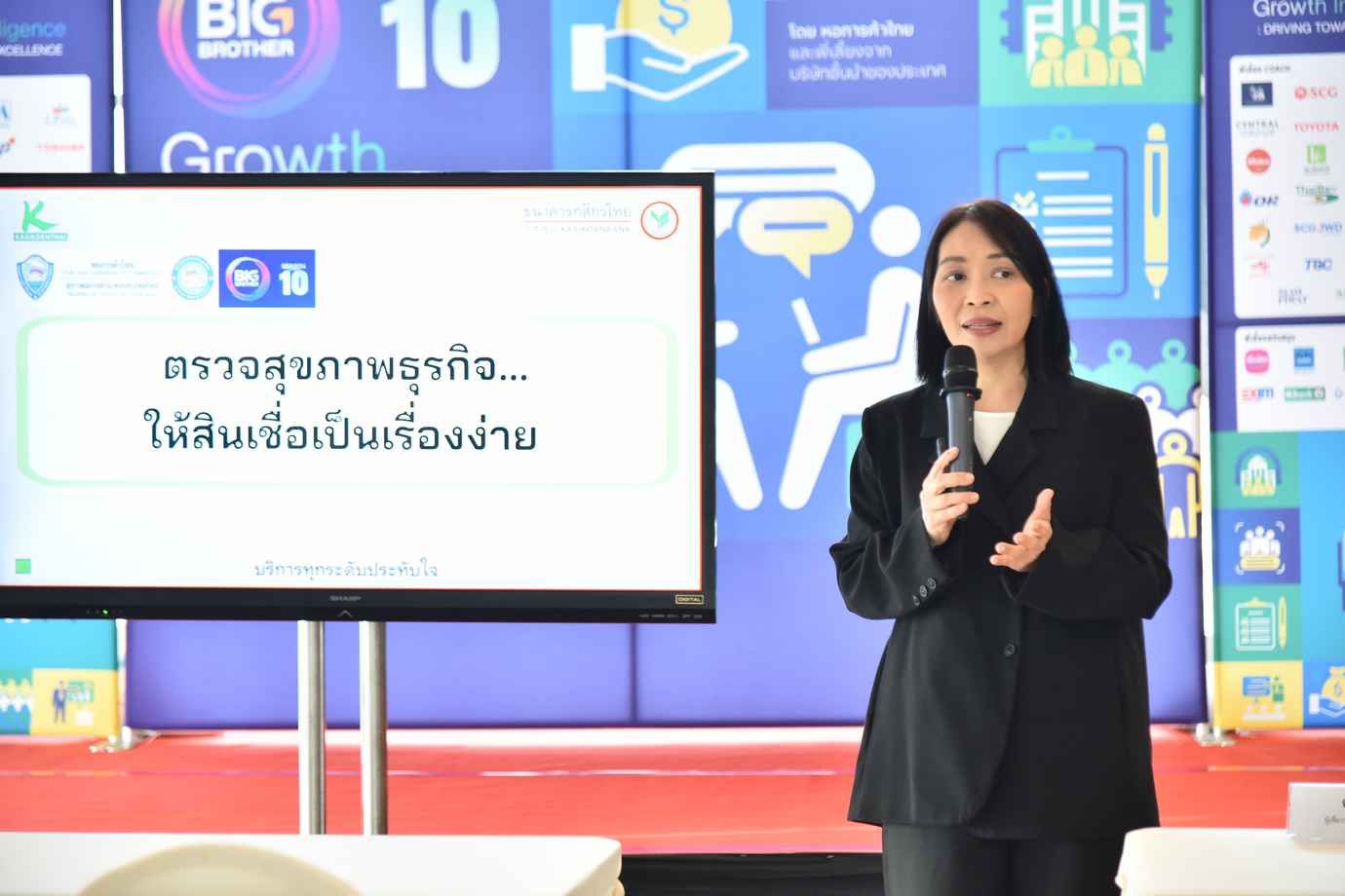 Woman presenting business health and credit solutions next to a screen displaying Thai text.