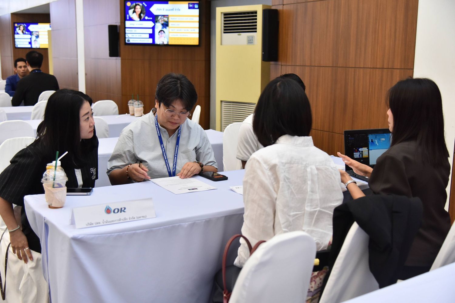Three individuals, two women and one man, are seated at a table discussing information on a laptop.