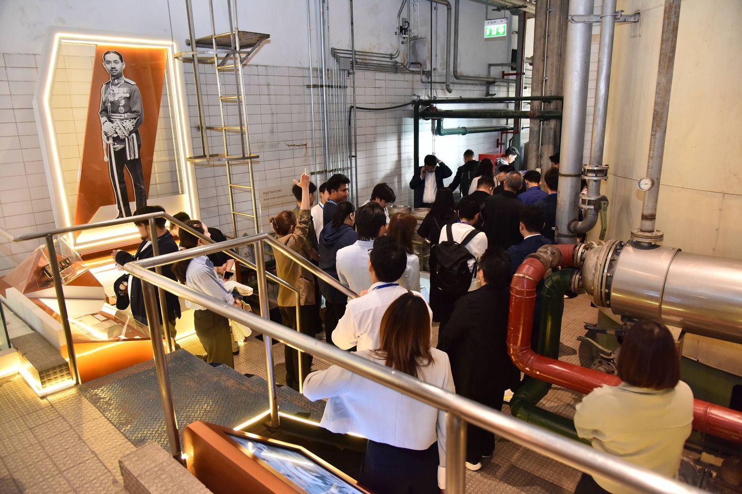 A group of visitors walks along a ramp next to an exhibit showing a historical figure.