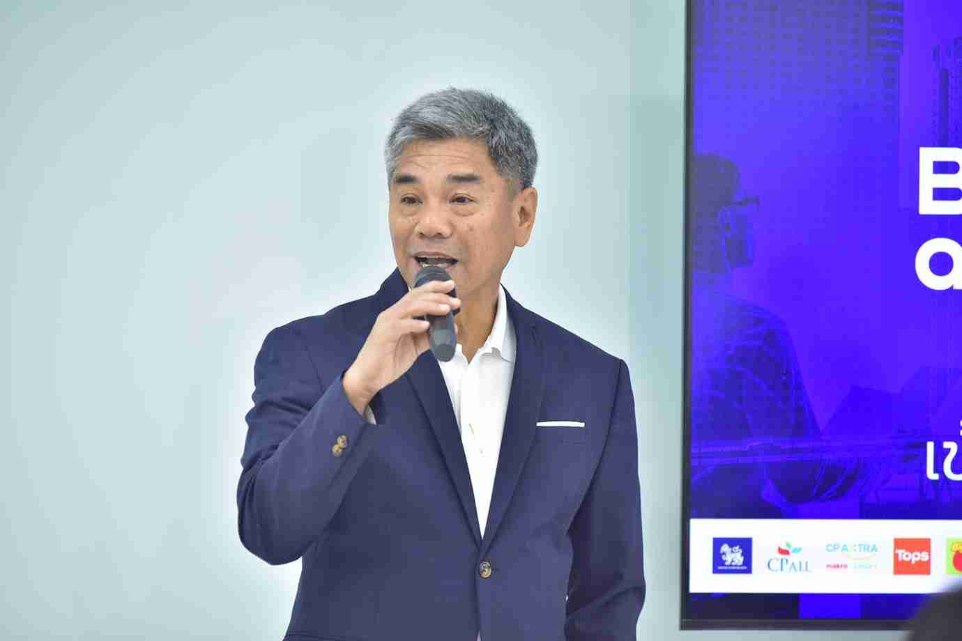 Professional man in a dark suit speaking into a microphone at an event.