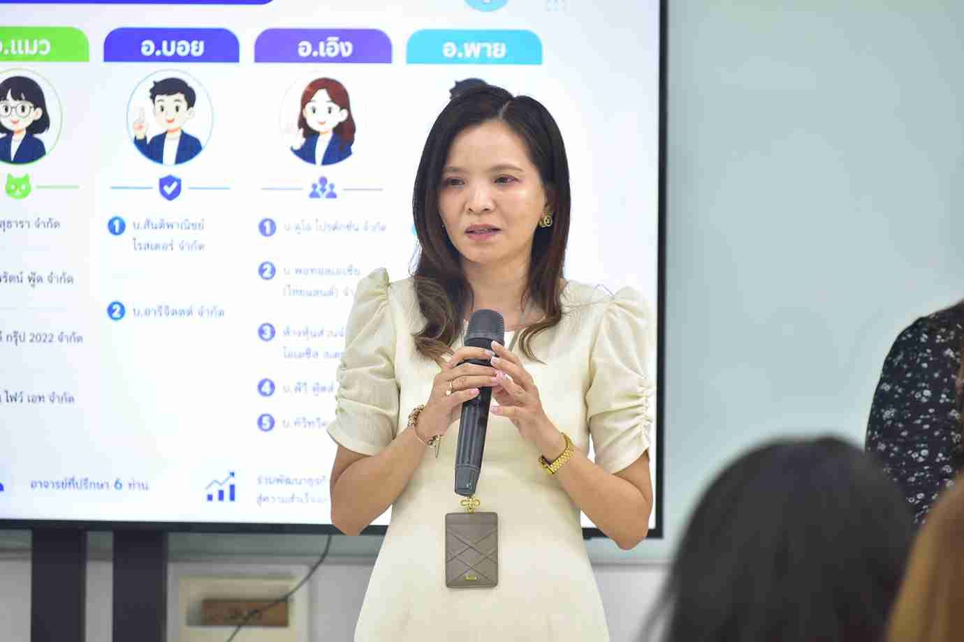 Woman speaks into a microphone during a presentation with a screen displaying data.