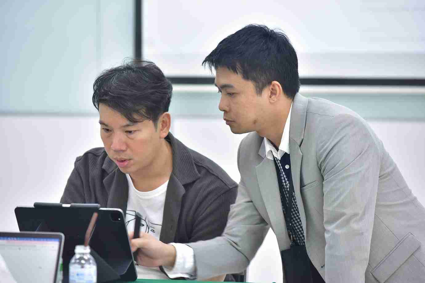 Two men collaborating and discussing content on a tablet device.