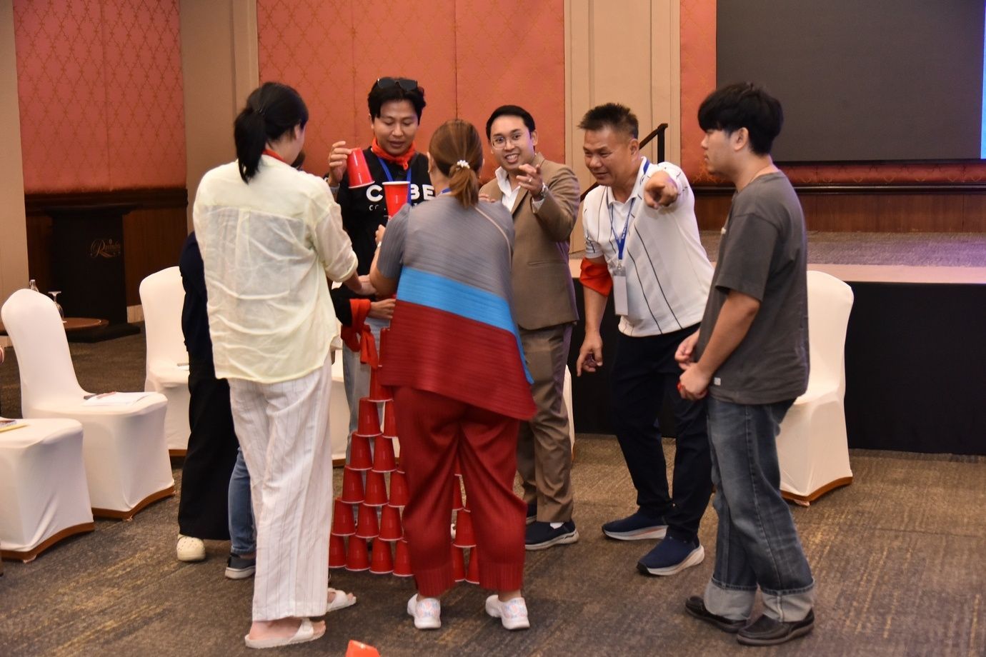 A group of people engaged in a team-building activity with red cups.
