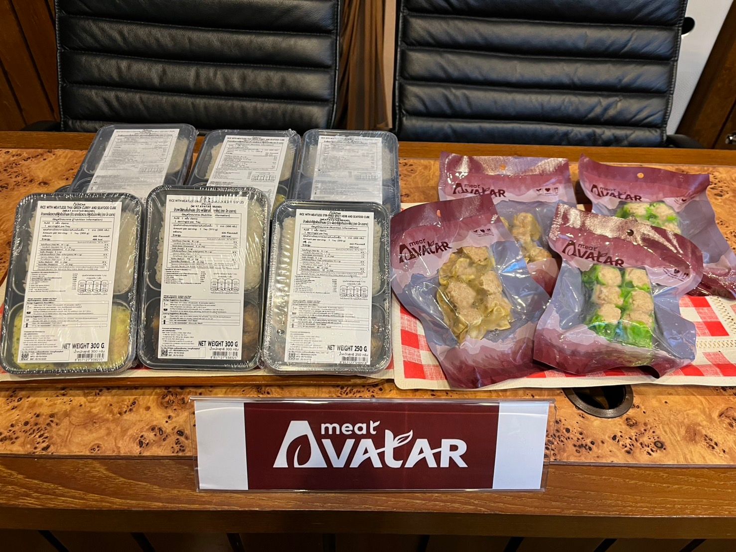 Various packaged meals and vacuum-sealed food items with a "meer AVATAR" sign on a table.