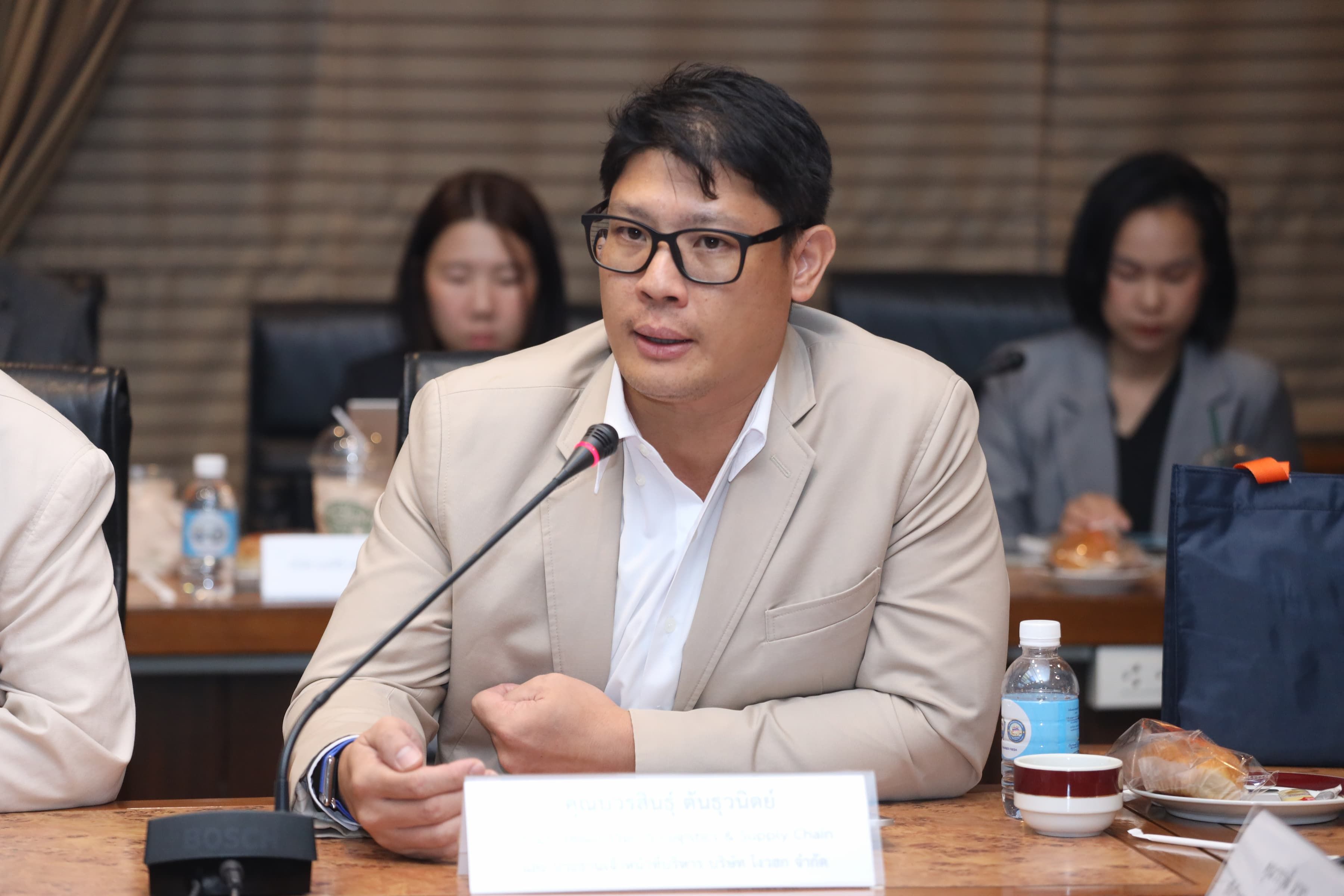 Man in glasses speaking into a microphone at a professional meeting.