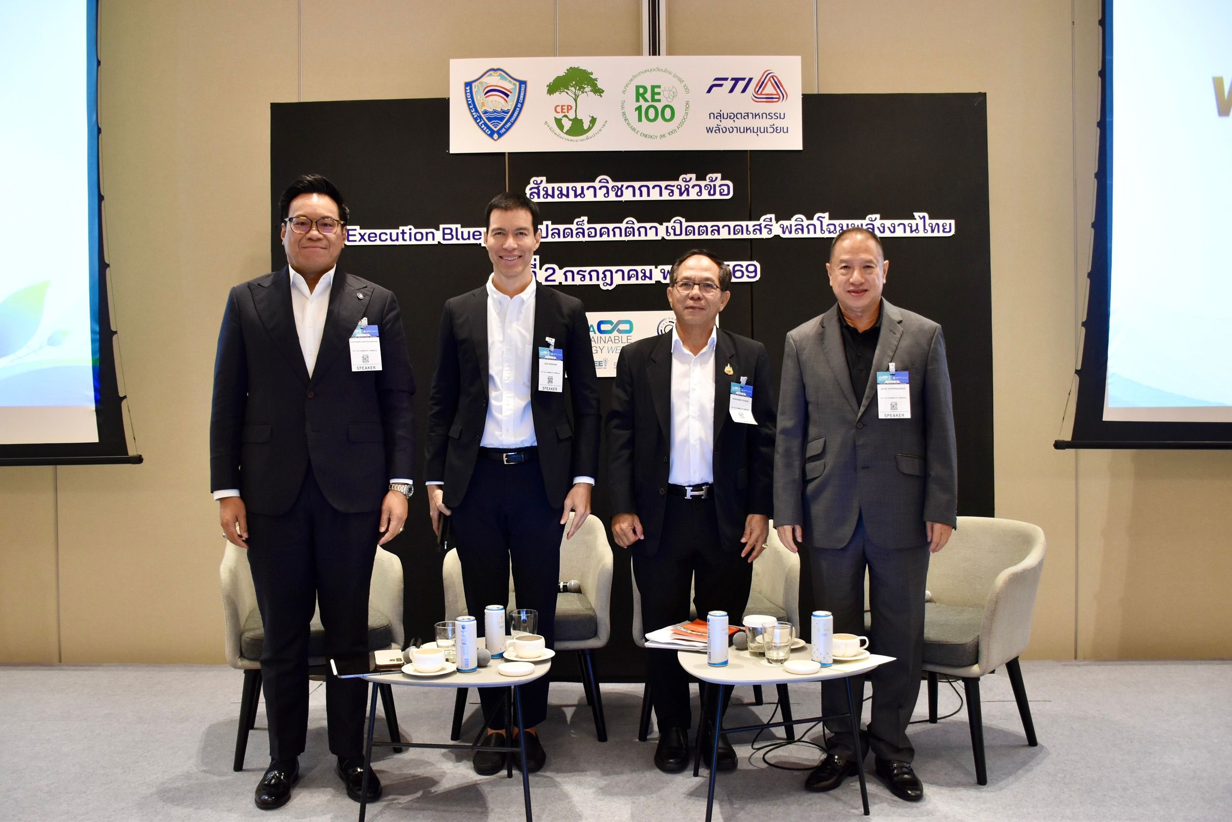 Four men in business suits stand on a stage during a professional event.