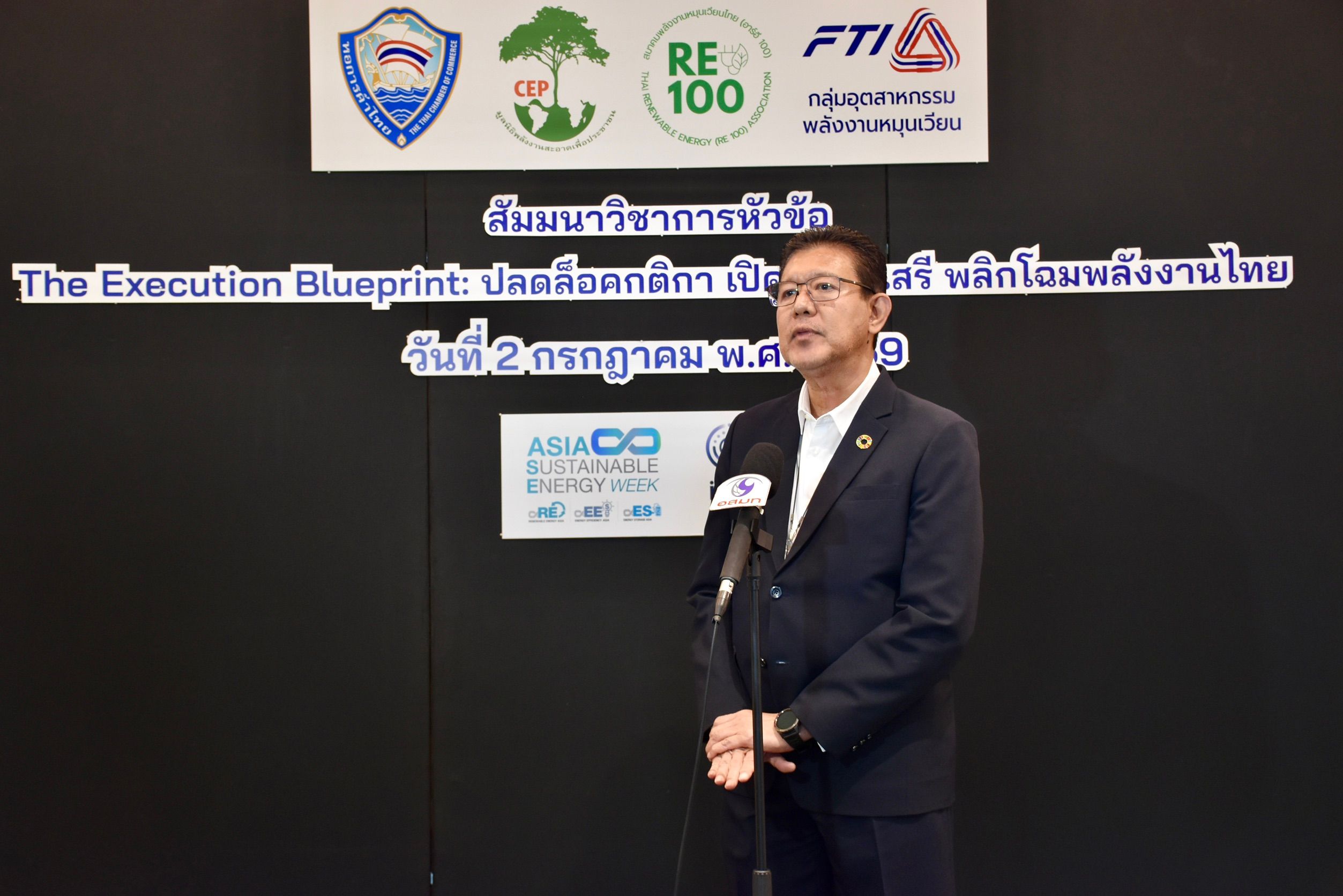 Man in a suit speaking at a podium with 'The Execution Blueprint' banner behind him.