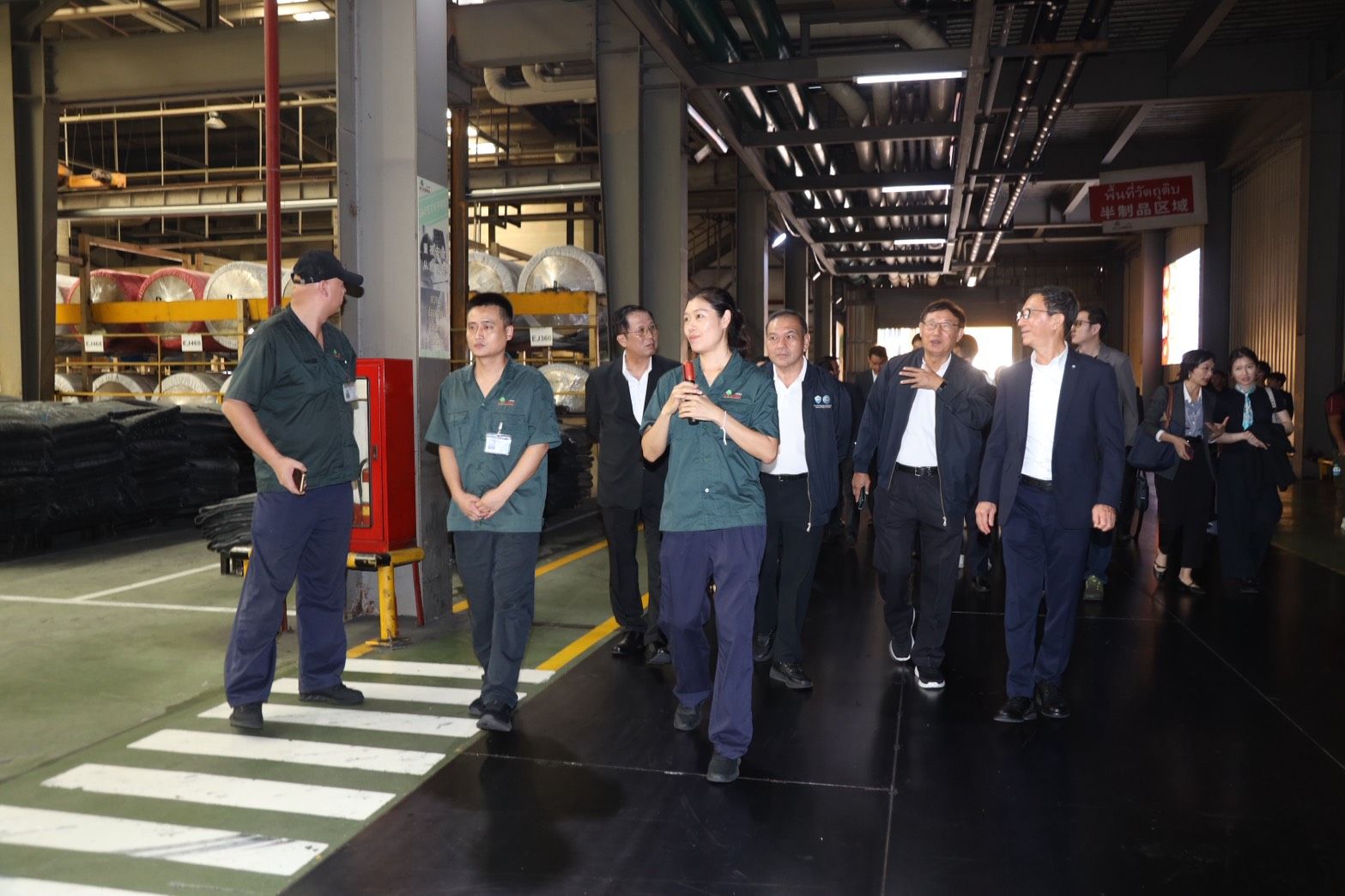 A team of workers and professionals walk through a factory floor on a tour.