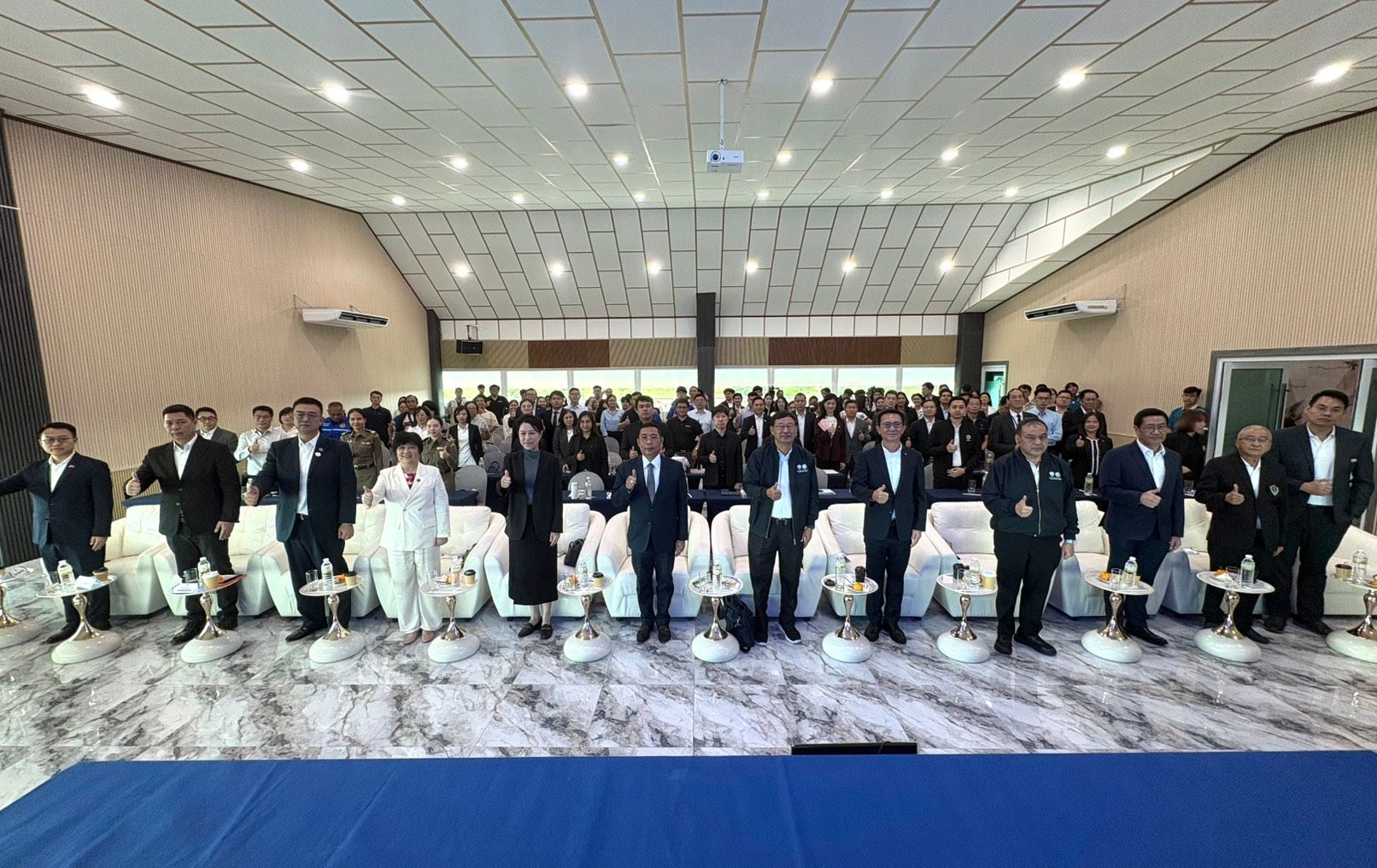 Large group of professionals standing in rows at a conference event in a modern hall.