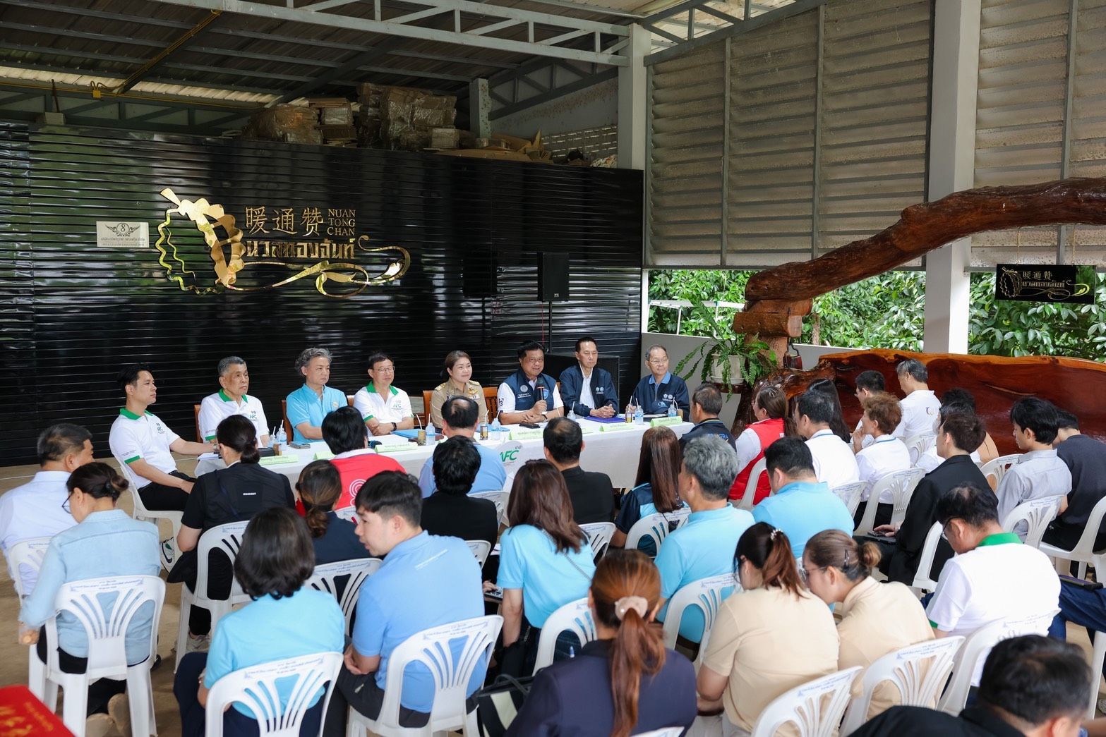 Officials present information to an audience at an indoor community meeting.