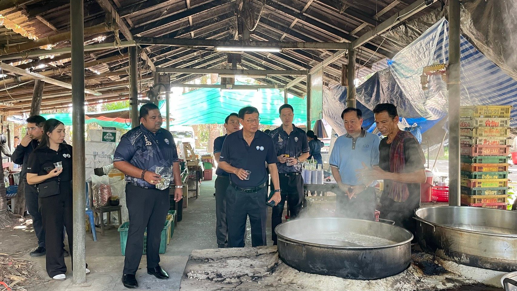 People gather around a large steaming pot on an outdoor stove.