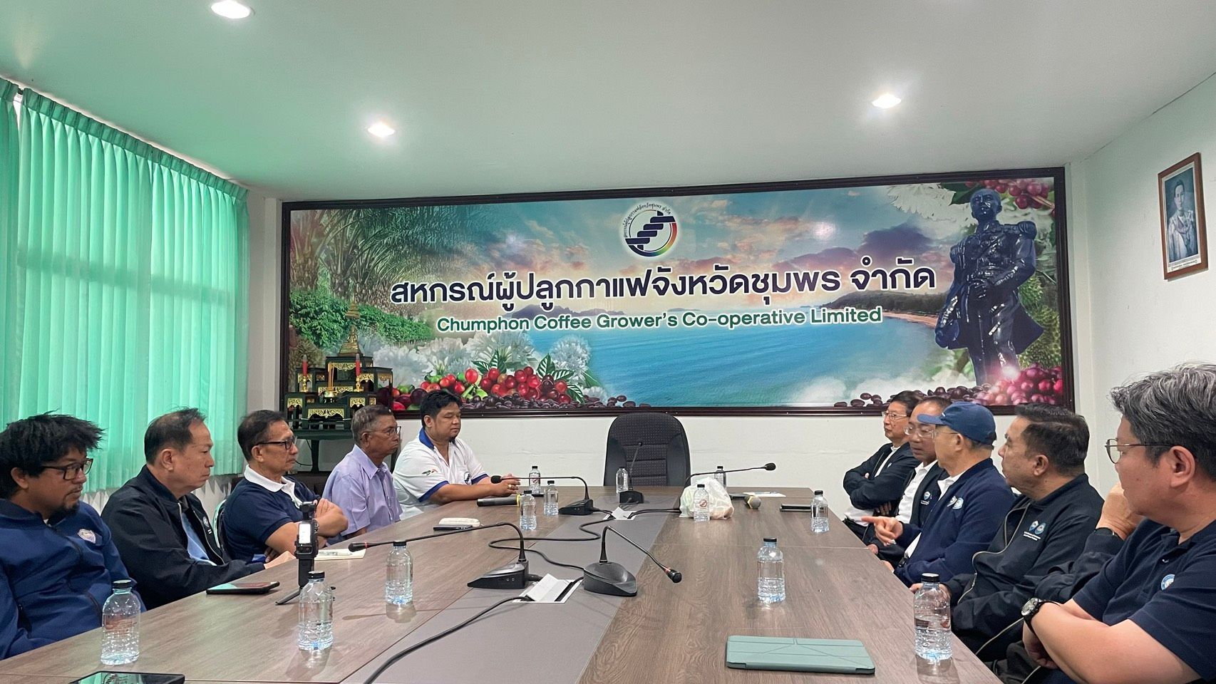 Officials seated around a conference table during a meeting with a large banner.