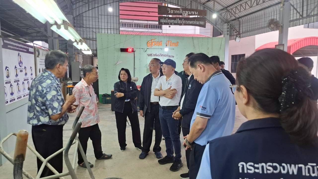 Group of officials and staff listening to a speaker in an indoor facility.