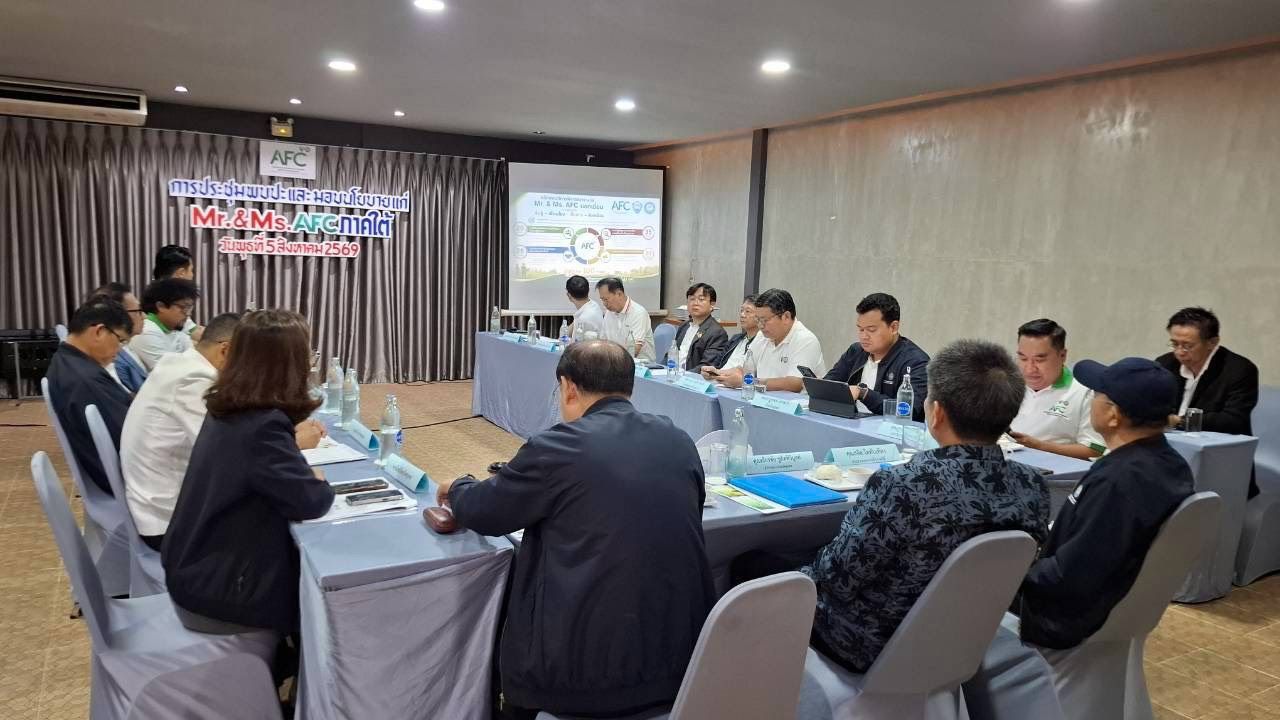 People seated around a conference table in a meeting room with a presentation screen.