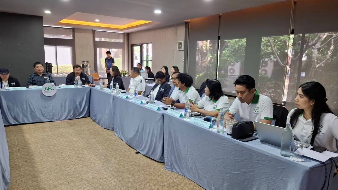 Group of professionals in a meeting room, seated around a U-shaped conference table.