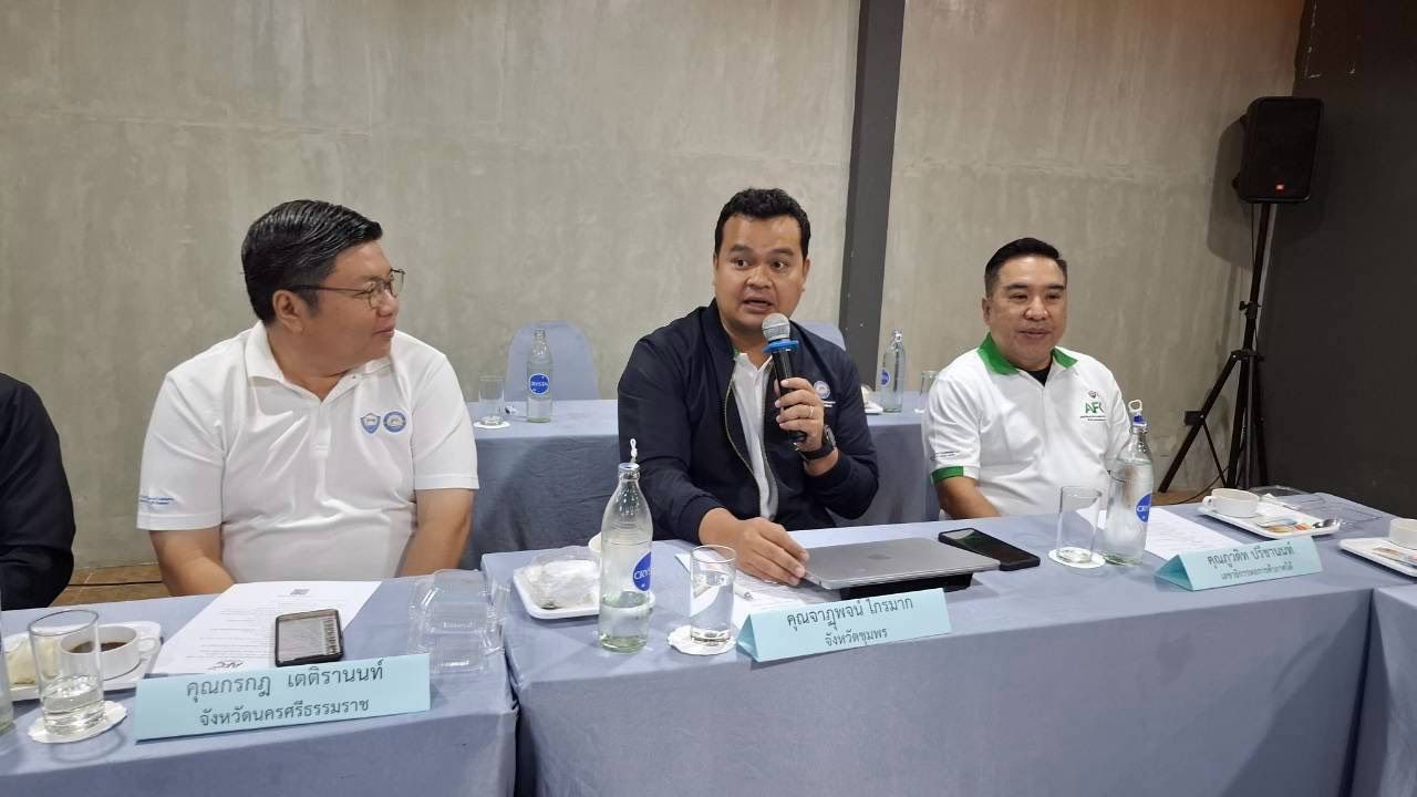 Three men at a conference table, one speaking into a microphone.