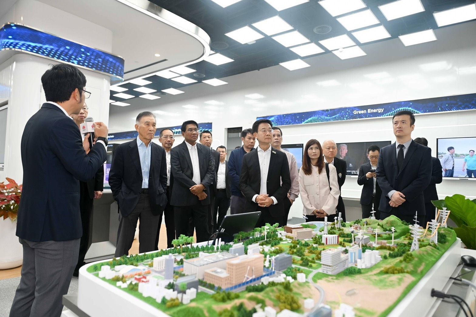 Professionals observe a presentation about an architectural model in a contemporary setting.