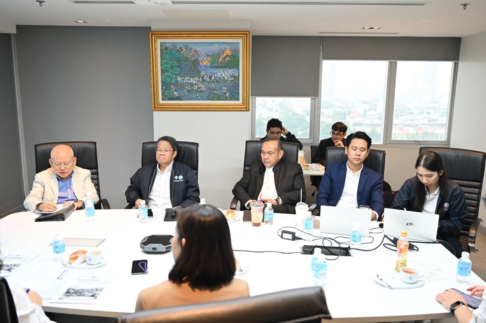 Several people sit around a long conference table, engaged in a business meeting.