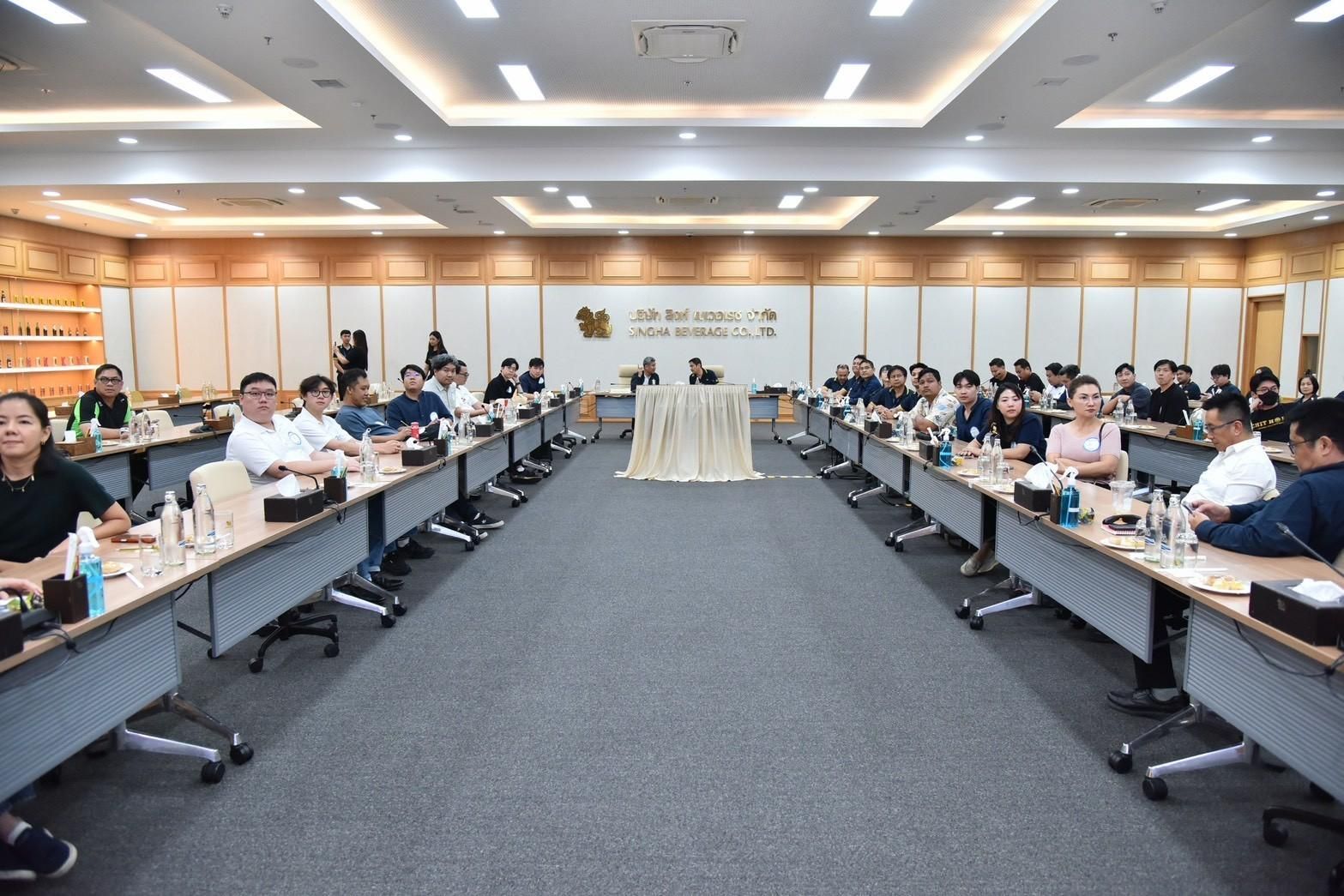 Professionals are seated at long tables in a well-lit conference room during a meeting.