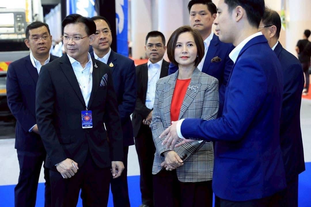 A group of formally dressed Asian business professionals attending an event, listening intently.