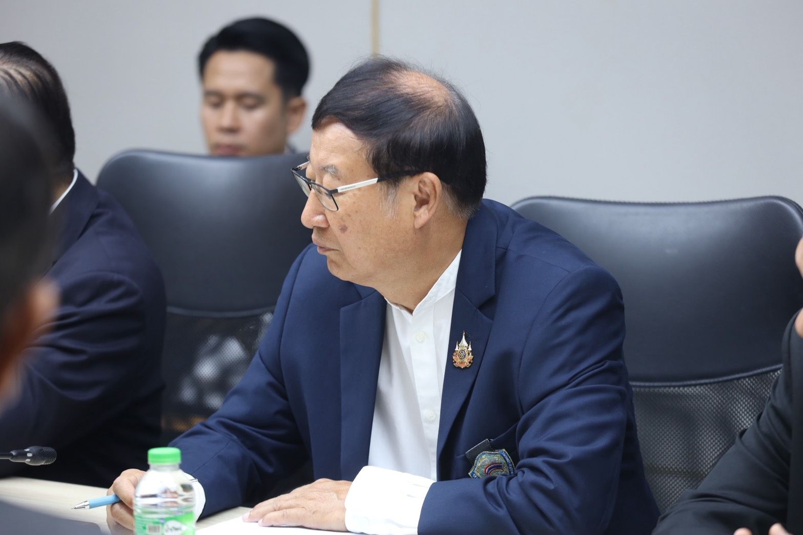 Man in blue suit and glasses listening during a professional meeting.