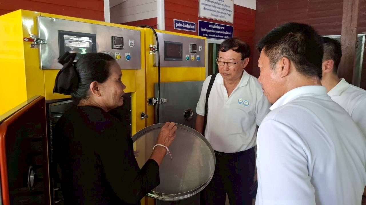 A woman explains the function of a large metal pot to three male observers.