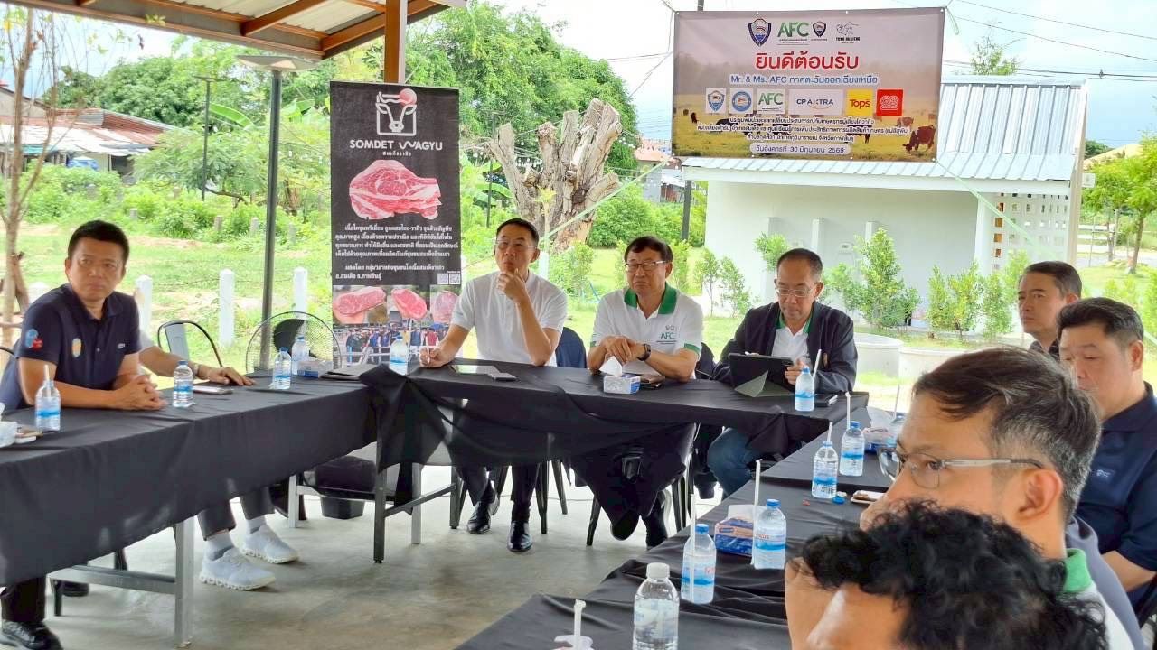 Group of men in a meeting, with a presentation screen and meat product banner visible.