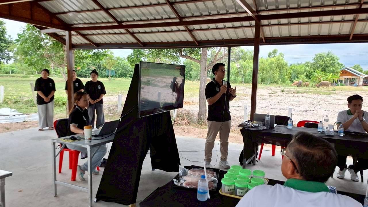 A man presents to a group of people outdoors, utilizing a large display screen.