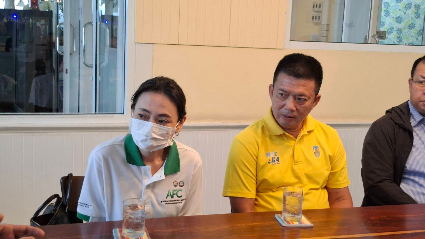 A woman in a mask and a man in a yellow shirt sit at a table.