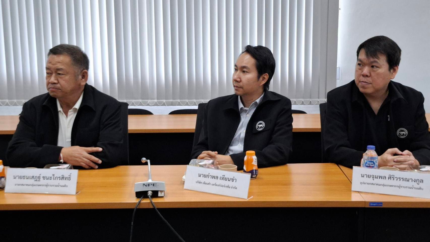 Three men in dark jackets seated at a conference table during a meeting.