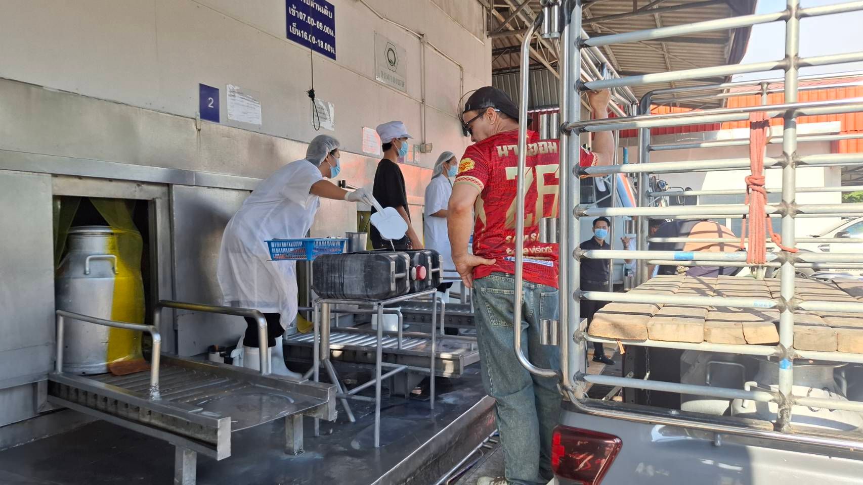 Workers in uniforms preparing and distributing food from large containers near a truck.