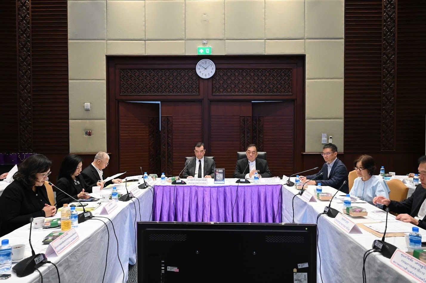 Professionals attend a formal business meeting around a U-shaped conference table.