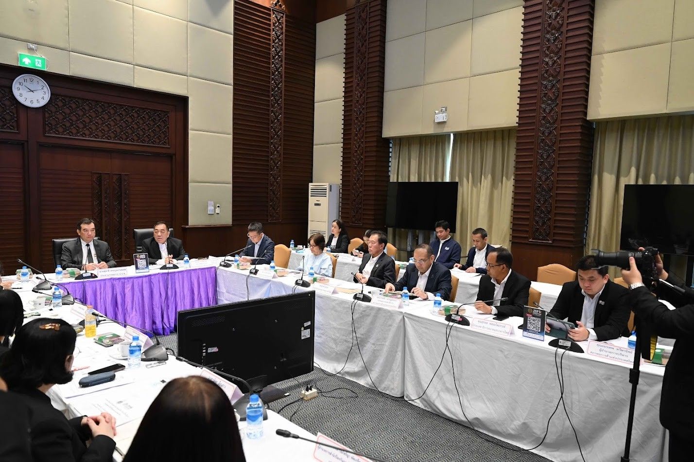 Professionals seated at conference tables during a formal meeting.