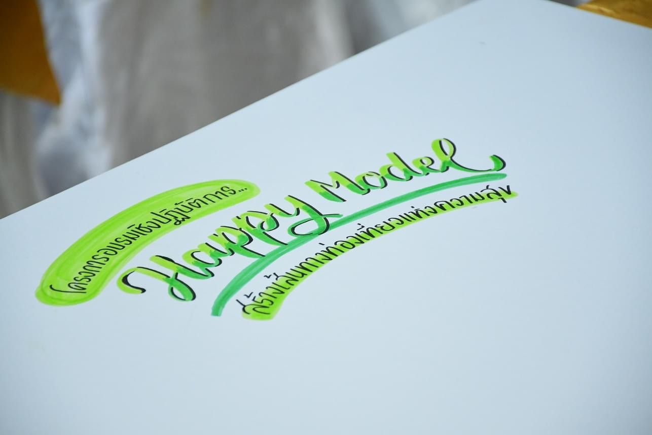 Green 'Happy Model' lettering in a cursive script, with additional Thai text on a white surface.