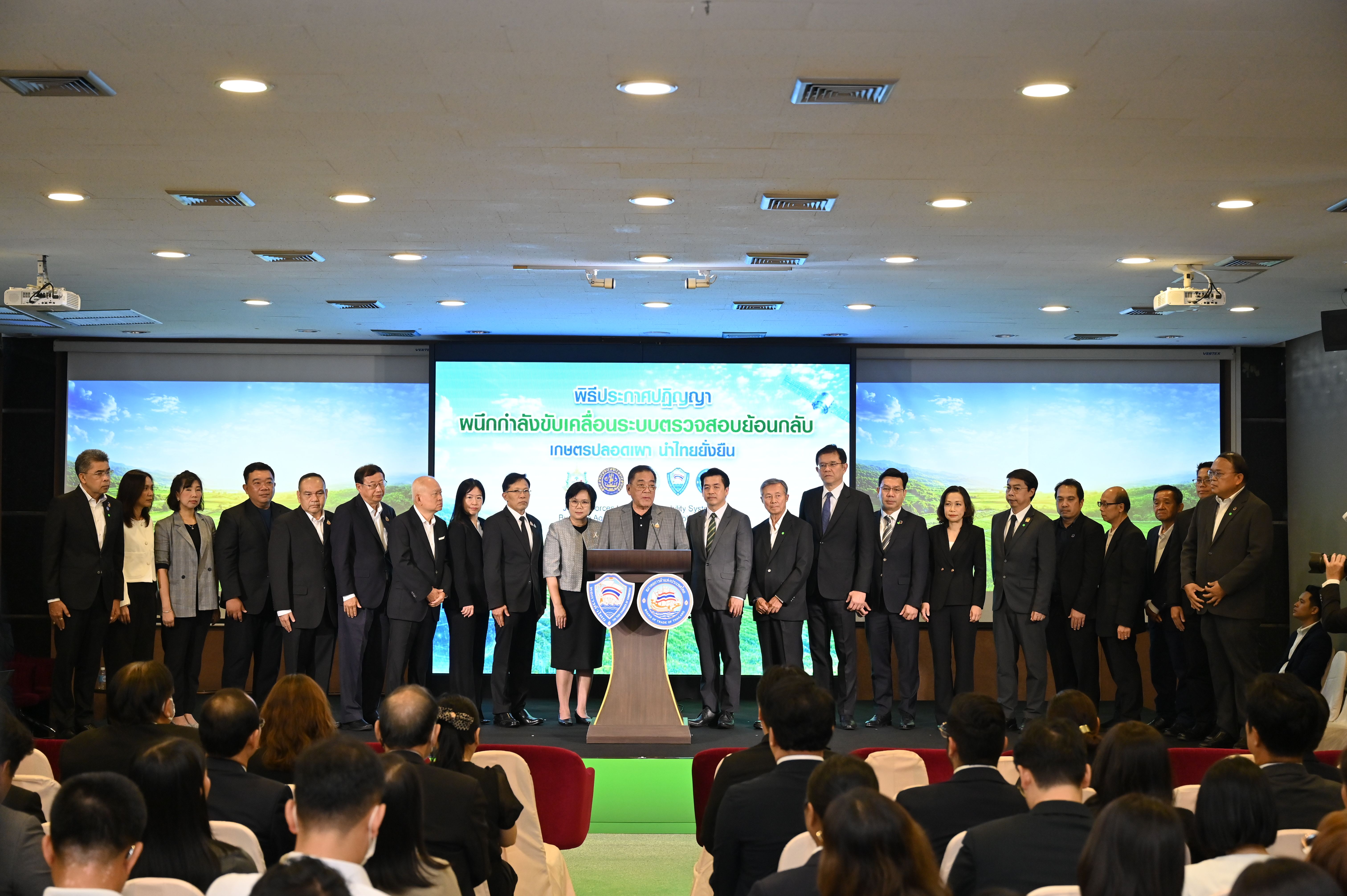 Professionals gather on a stage during an event with a large screen and audience.