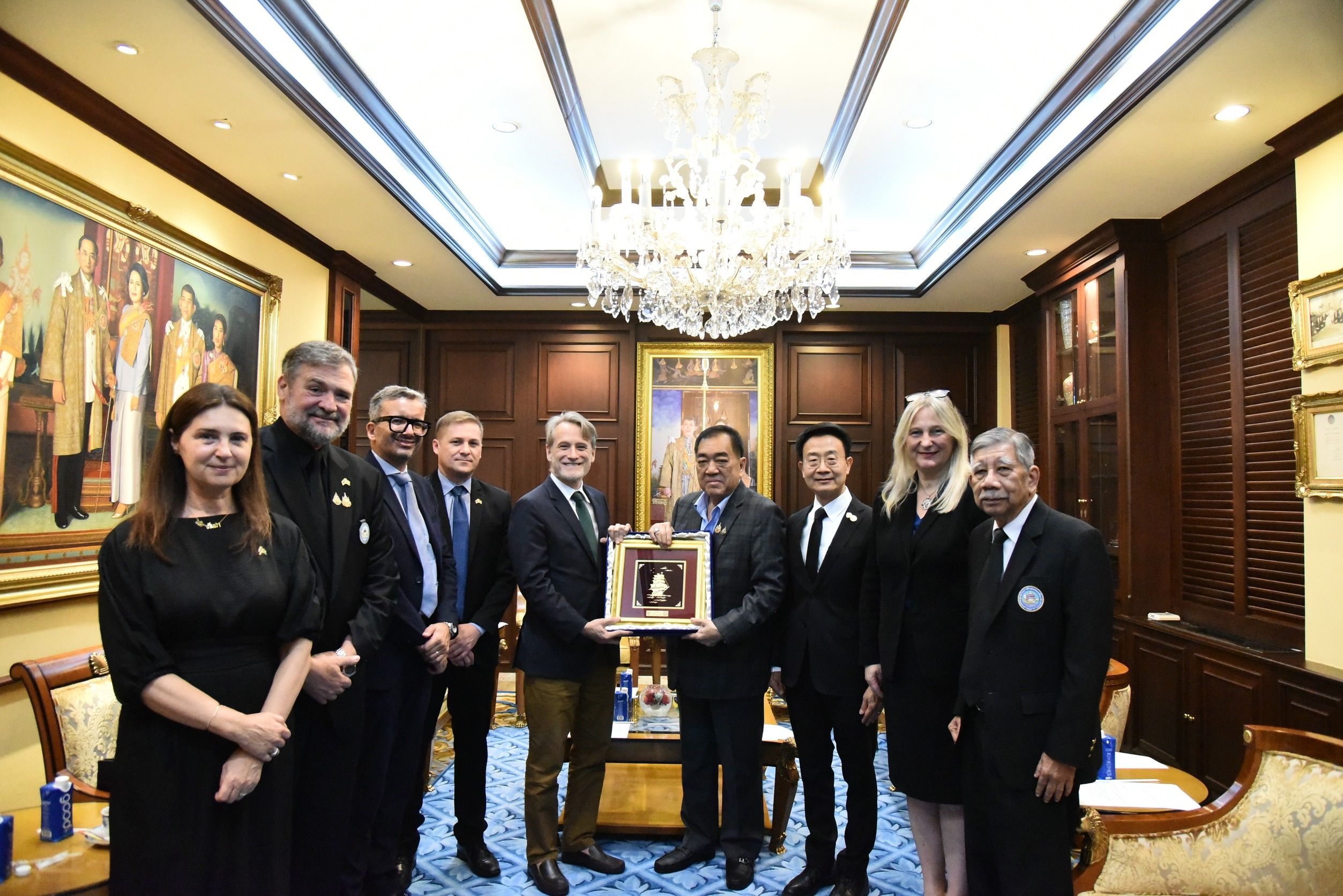 A diverse group of ten people exchanging an award in a formal office setting.