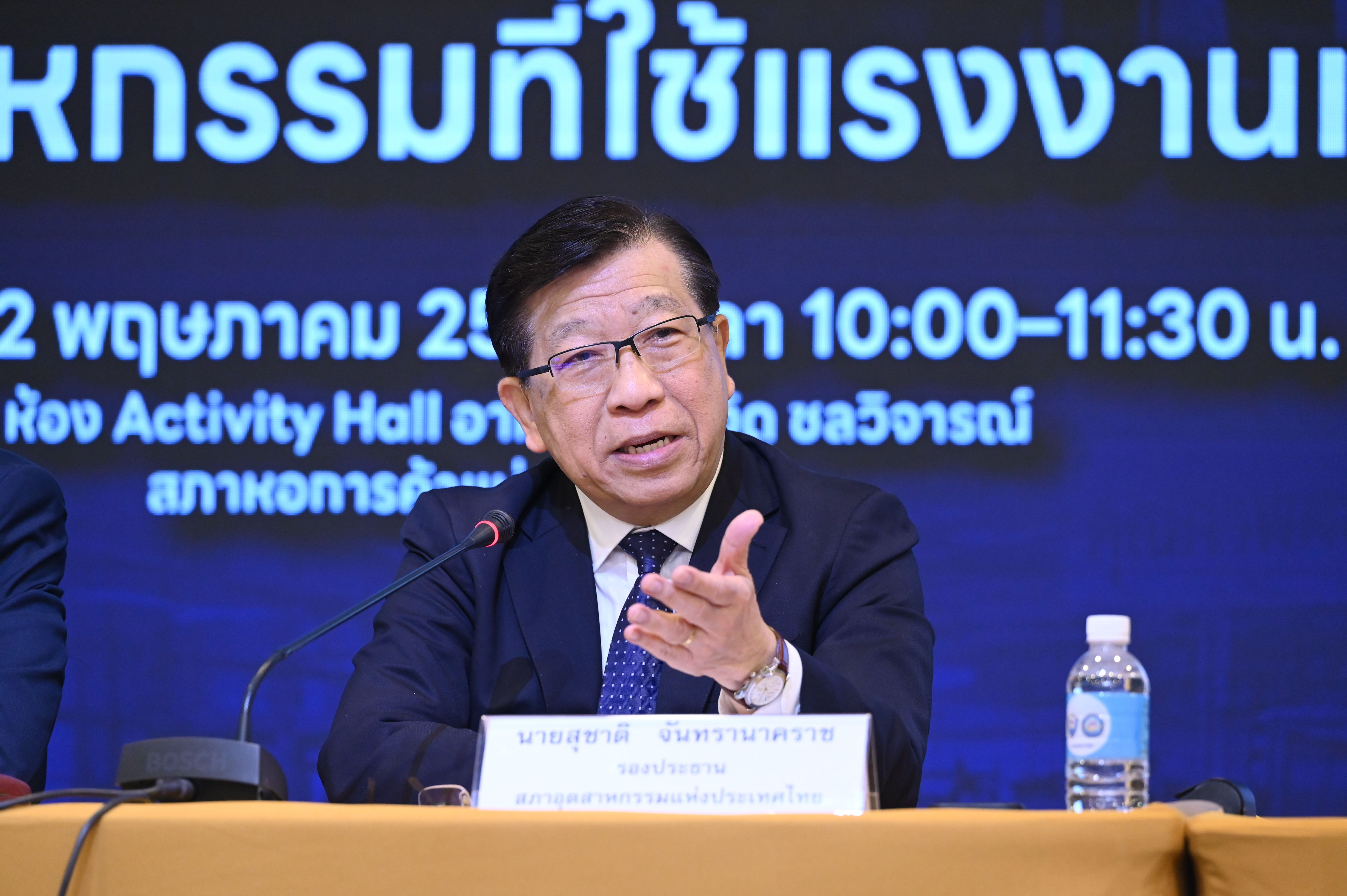 Man in a suit and glasses speaking at a podium with a microphone.