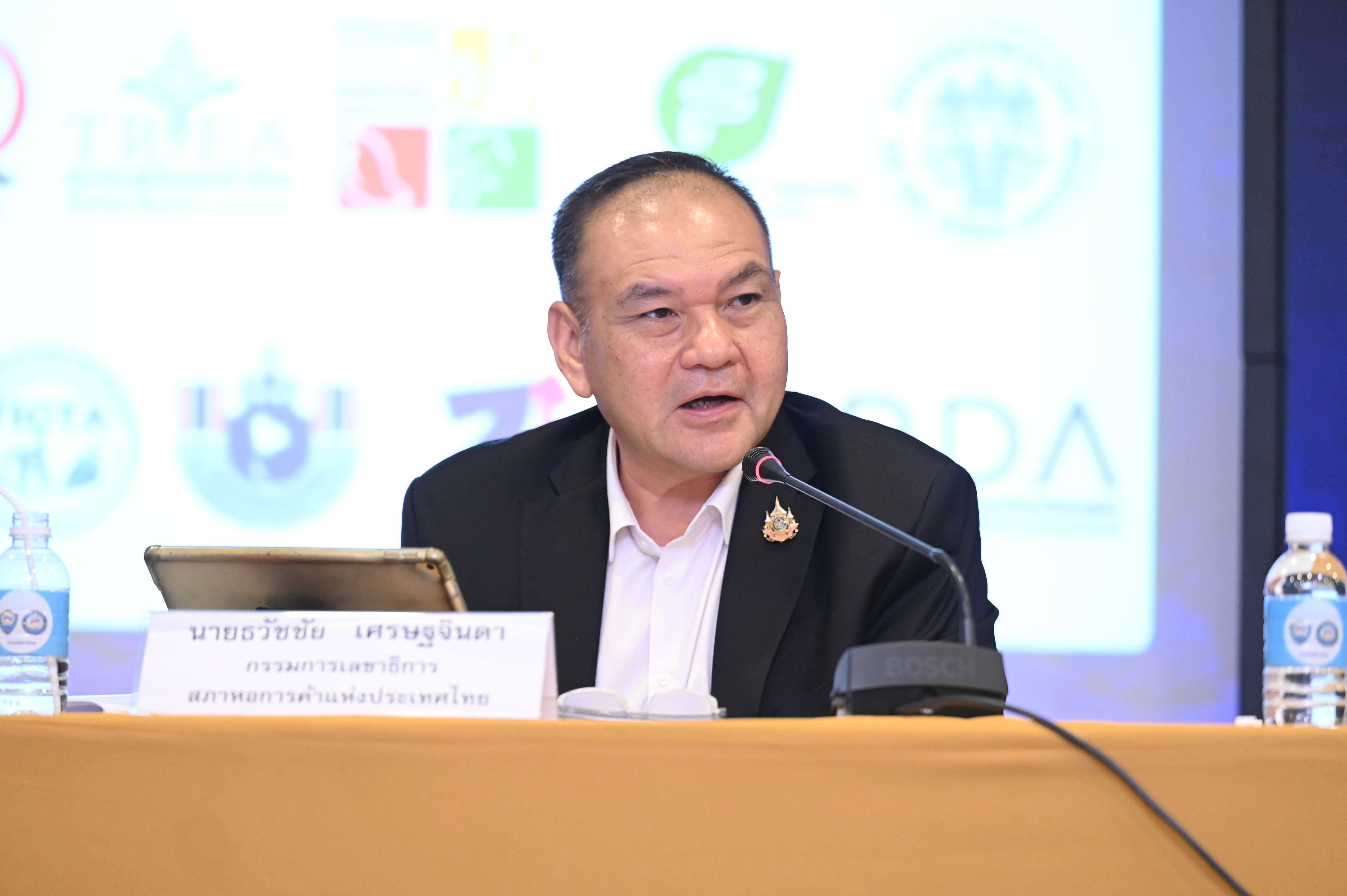 Mr. Prasert Sakulratchaporn speaks into a microphone at a conference podium.