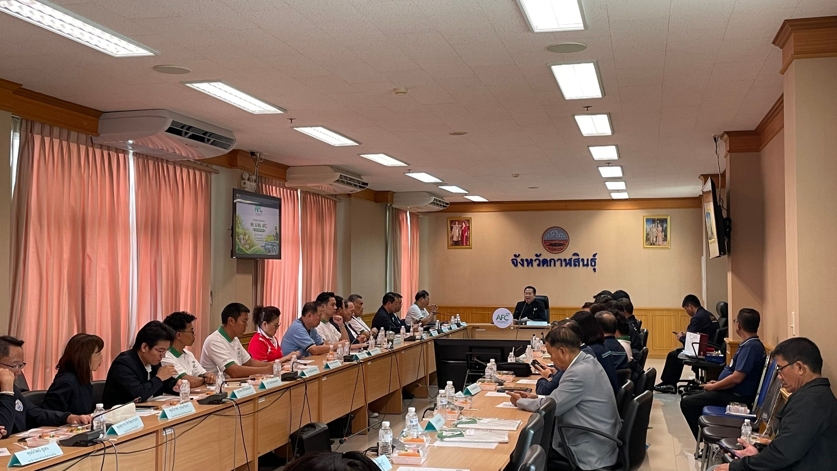 Attendees sit around a long table in a well-lit conference room during a meeting.