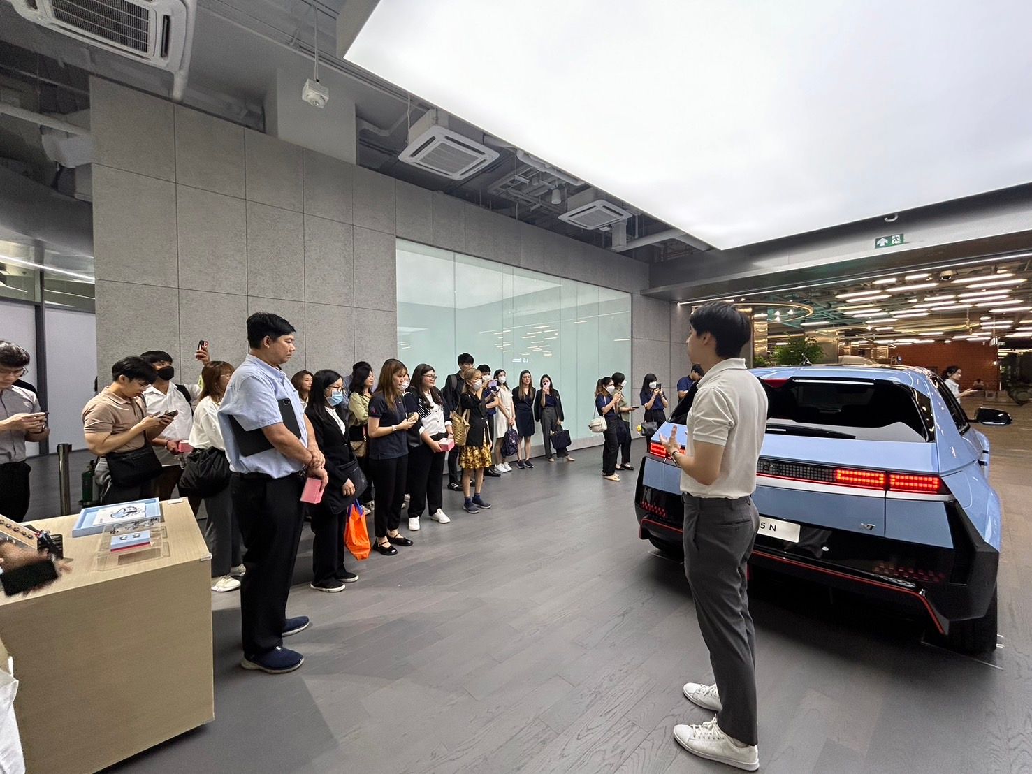 Speaker presenting a modern electric vehicle to an attentive audience in a showroom.