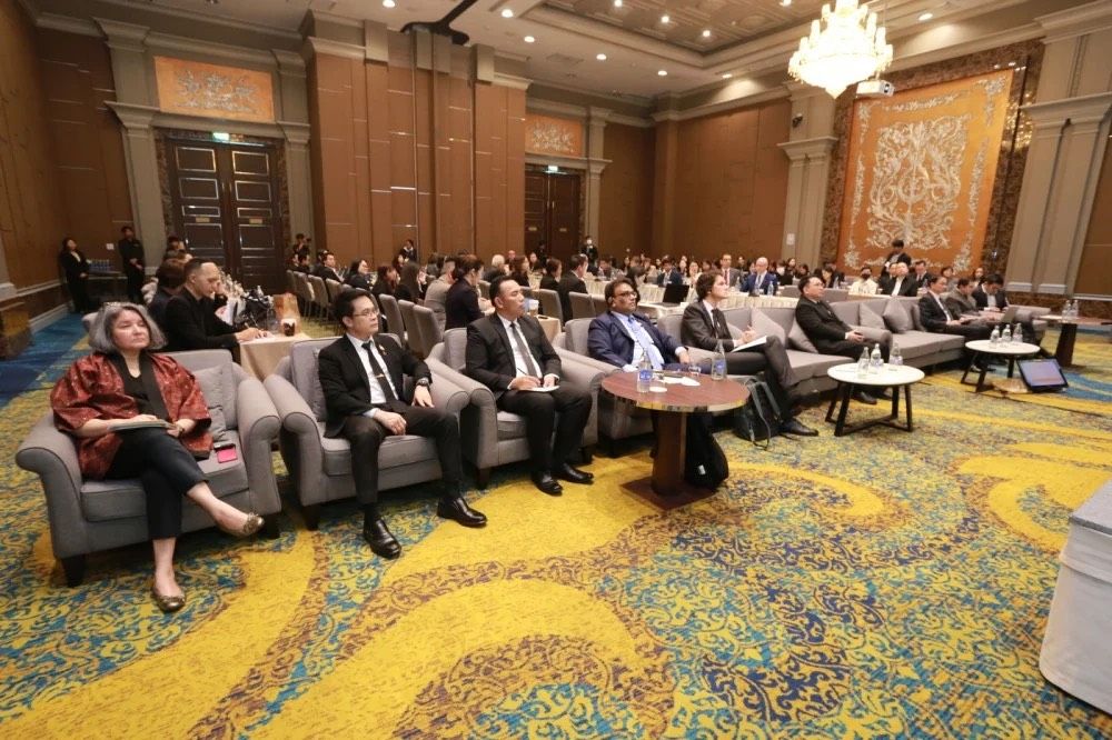 An audience in a large, elegant conference room attending a presentation.