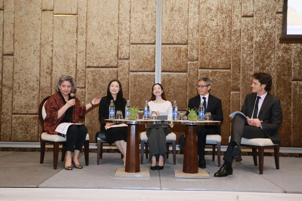 Five panelists, four women and one man, participate in a discussion on stage.
