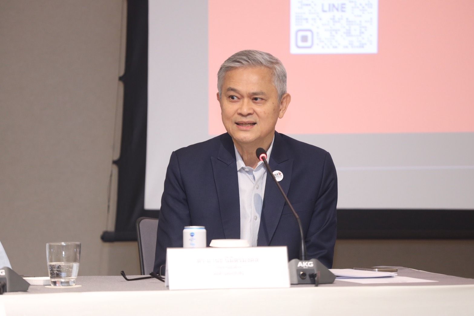 A distinguished man with gray hair speaks at a podium with a microphone.