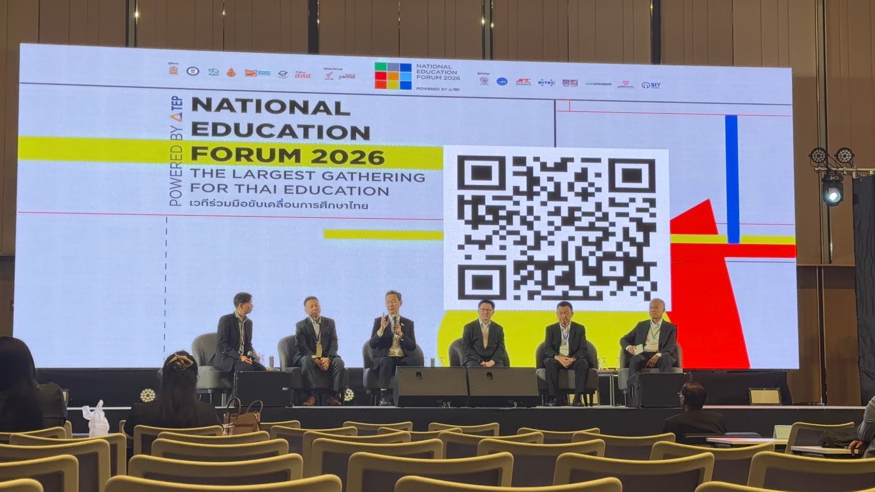 Panelists present at the 'National Education Forum 2026' event with a large screen and QR code.