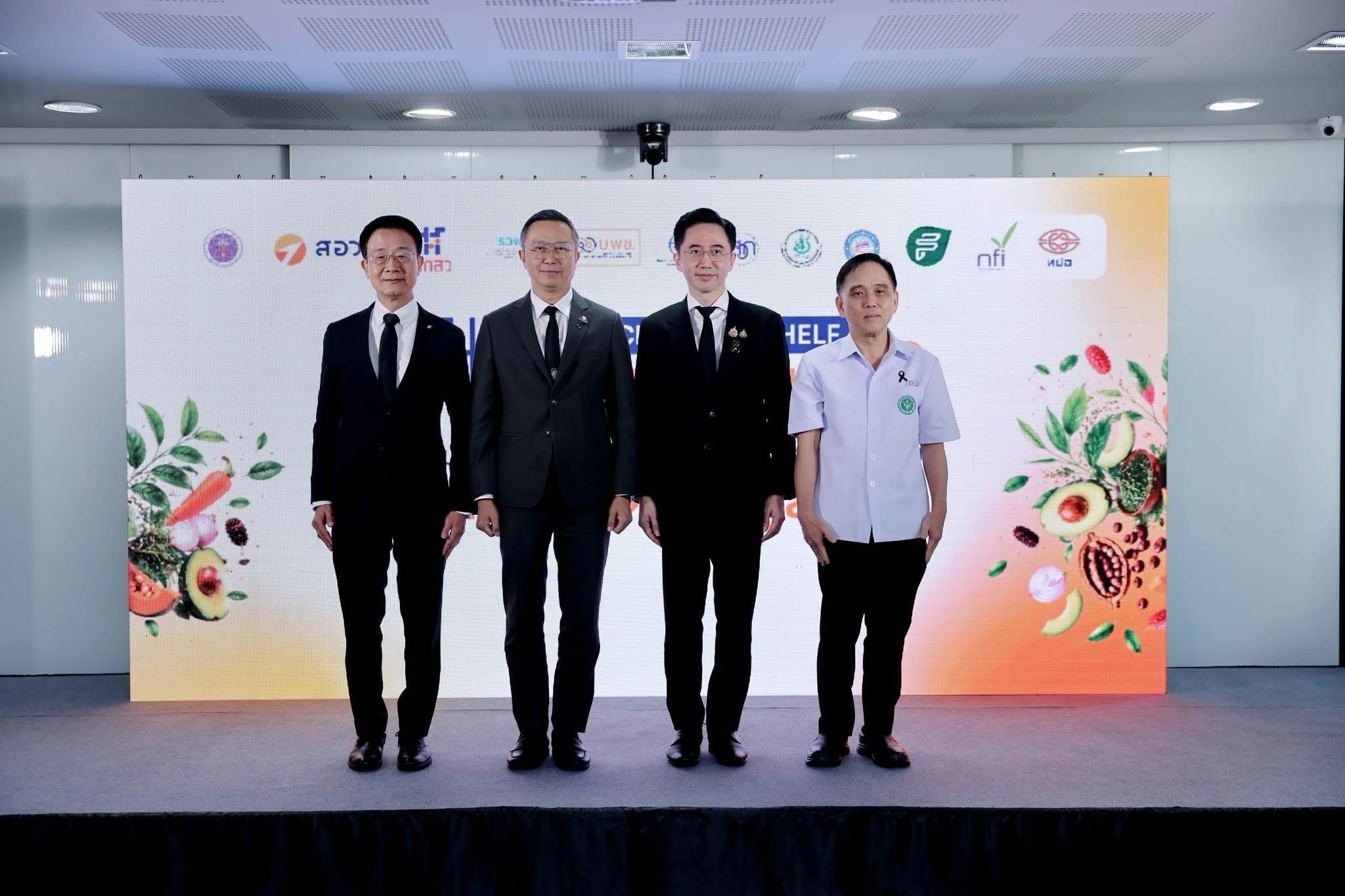 Four men in suits and a polo shirt stand before a food-themed backdrop.