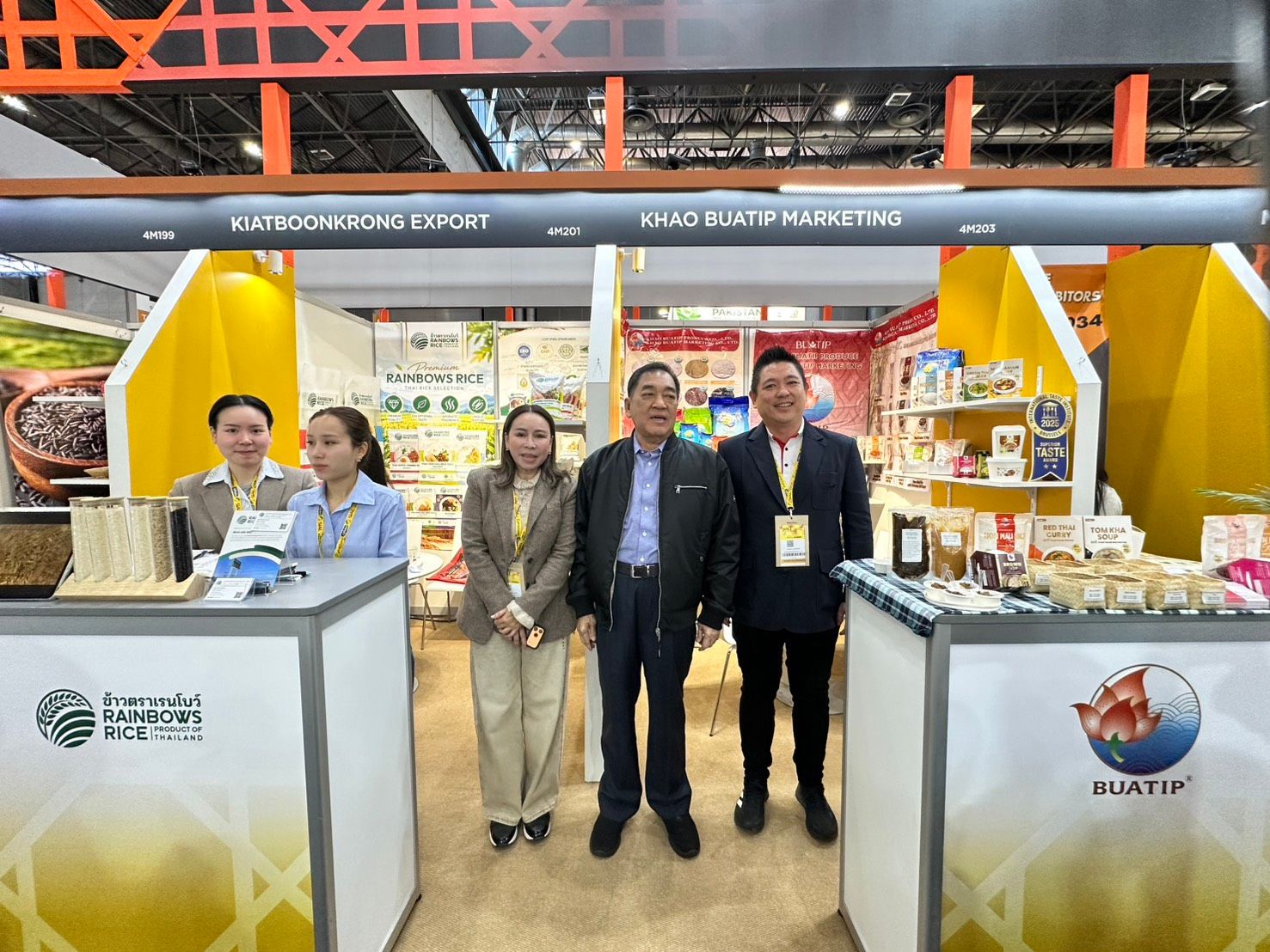 Five people stand proudly at brightly lit exhibition booths showcasing various products.