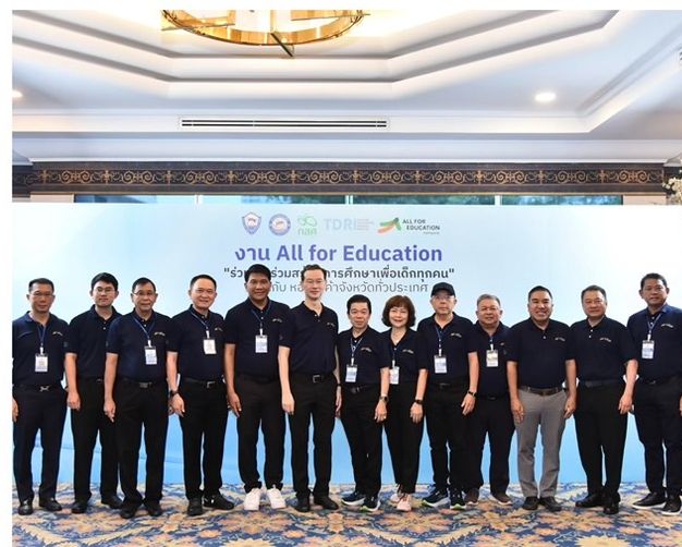 Group of 15 professionals in dark polo shirts posing before an 'All for Education' banner.